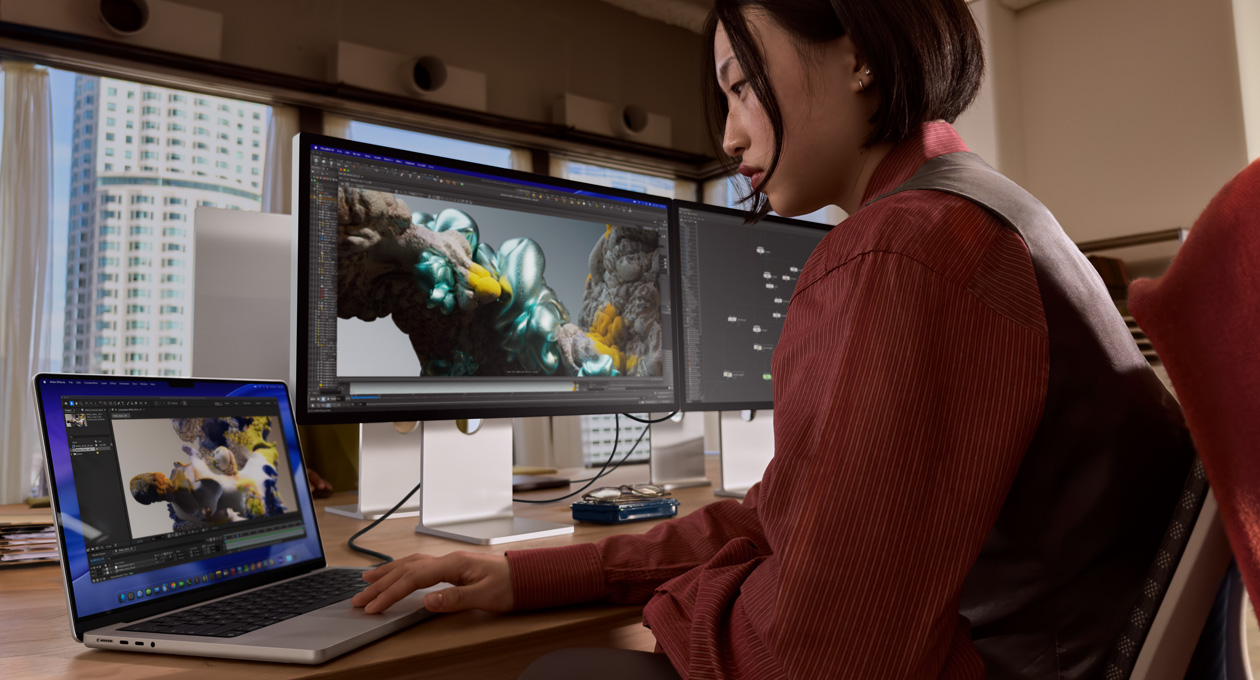 Човек в офис работи с MacBook лаптоп, който е свързан със Studio Display XDR чрез Thunderbolt 5 порт