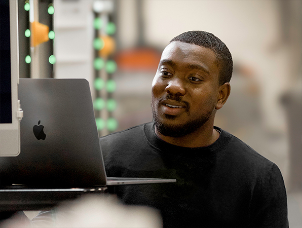 In an Apple manufacturing facility, two employees examine aluminum MacBook shells on titanium anodizing racks.