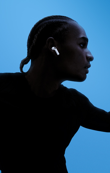 Una persona con unos AirPods 5, brazos extendidos, fondo colorido