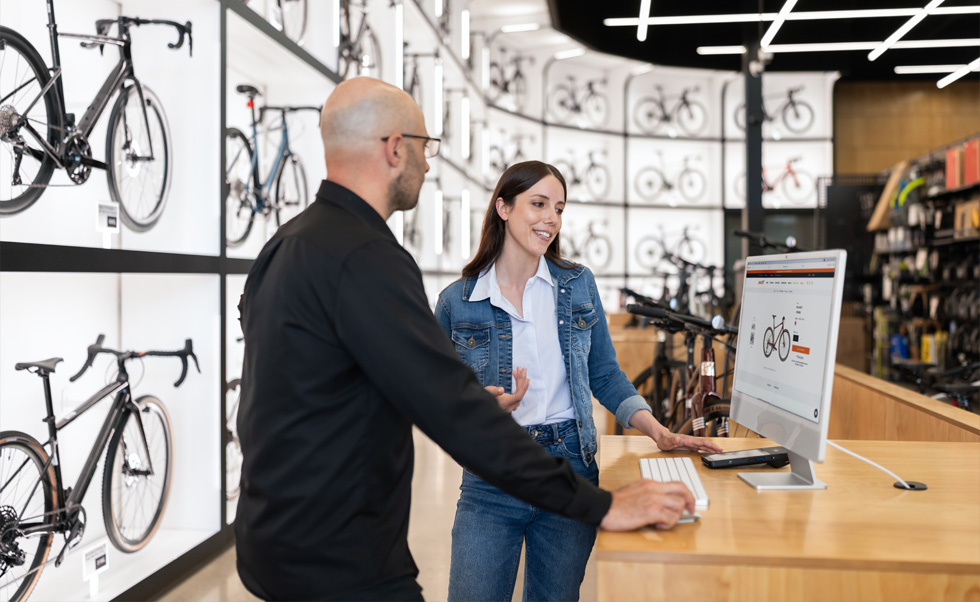 Julien Sicuro, gerente de tienda, ayuda a una clienta a elegir una bicicleta en la nítida pantalla Retina de un iMac.