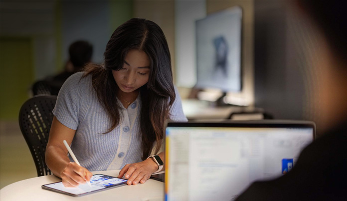 Estudante universitária usa o Apple Pencil para tomar notas no iPad num laboratório de tecnologia