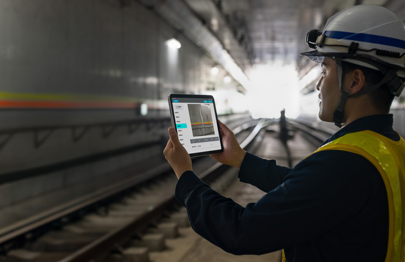 東京メトロのトンネル内で、同僚に見守られながら、保守作業員がiPadで線路を撮影している
