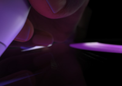 Un utilizator ține un Apple Pencil Pro în poziție de scris. Vârful apasă pe un ecran pe care sunt afișate linii groase desenate cu violet deschis.