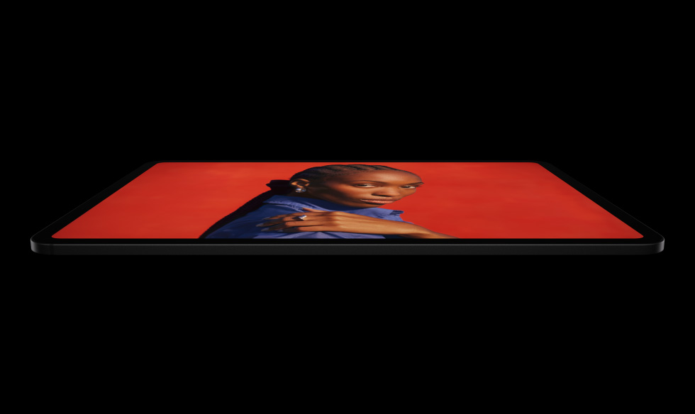 iPad Pro, πλαϊνή εξωτερική όψη, οριζόντιος προσανατολισμός, Διαστημικό Μαύρο, στρογγυλεμένες γωνίες, μαύρο πλαίσιο οθόνης, οθόνη που εμφανίζει μια οθόνη σε ζωηρό κόκκινο χρώμα με ένα άτομο να ποζάρει με το χέρι του στον ώμο, φορώντας ένα μπλε πουκάμισο