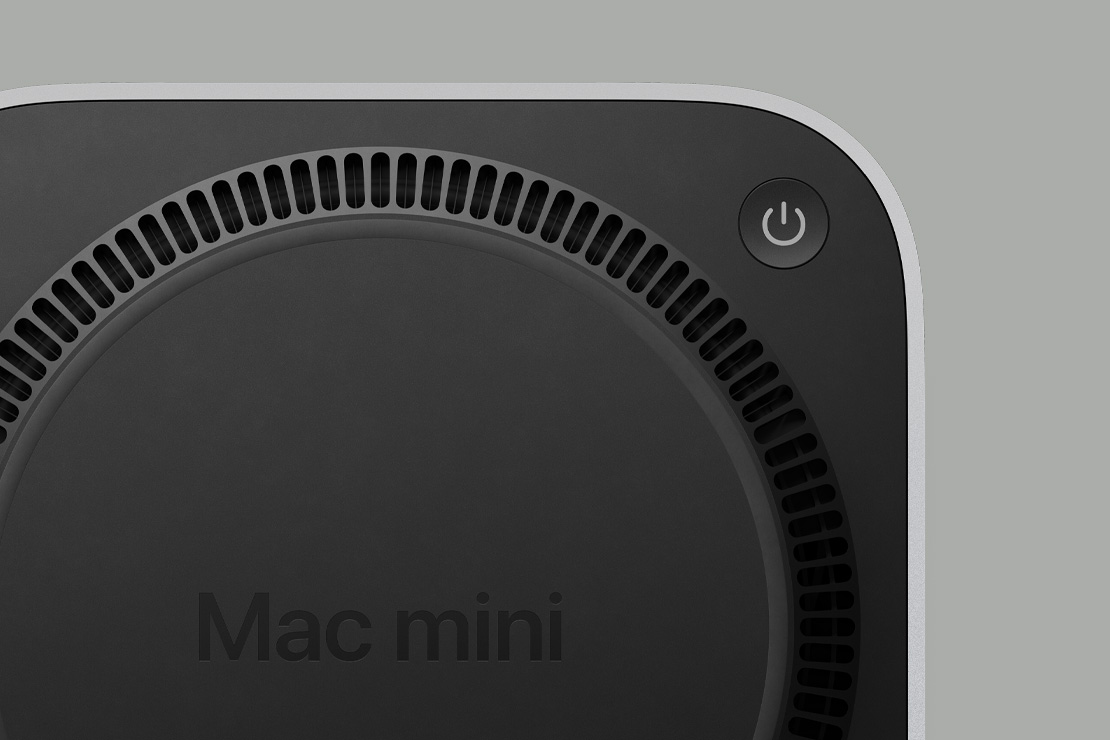 Juodos spalvos „Mac mini“ apatinė dalis, kurioje matyti įjungimo mygtukas ir apskrita ventiliatoriaus formos ventiliacijos sistema