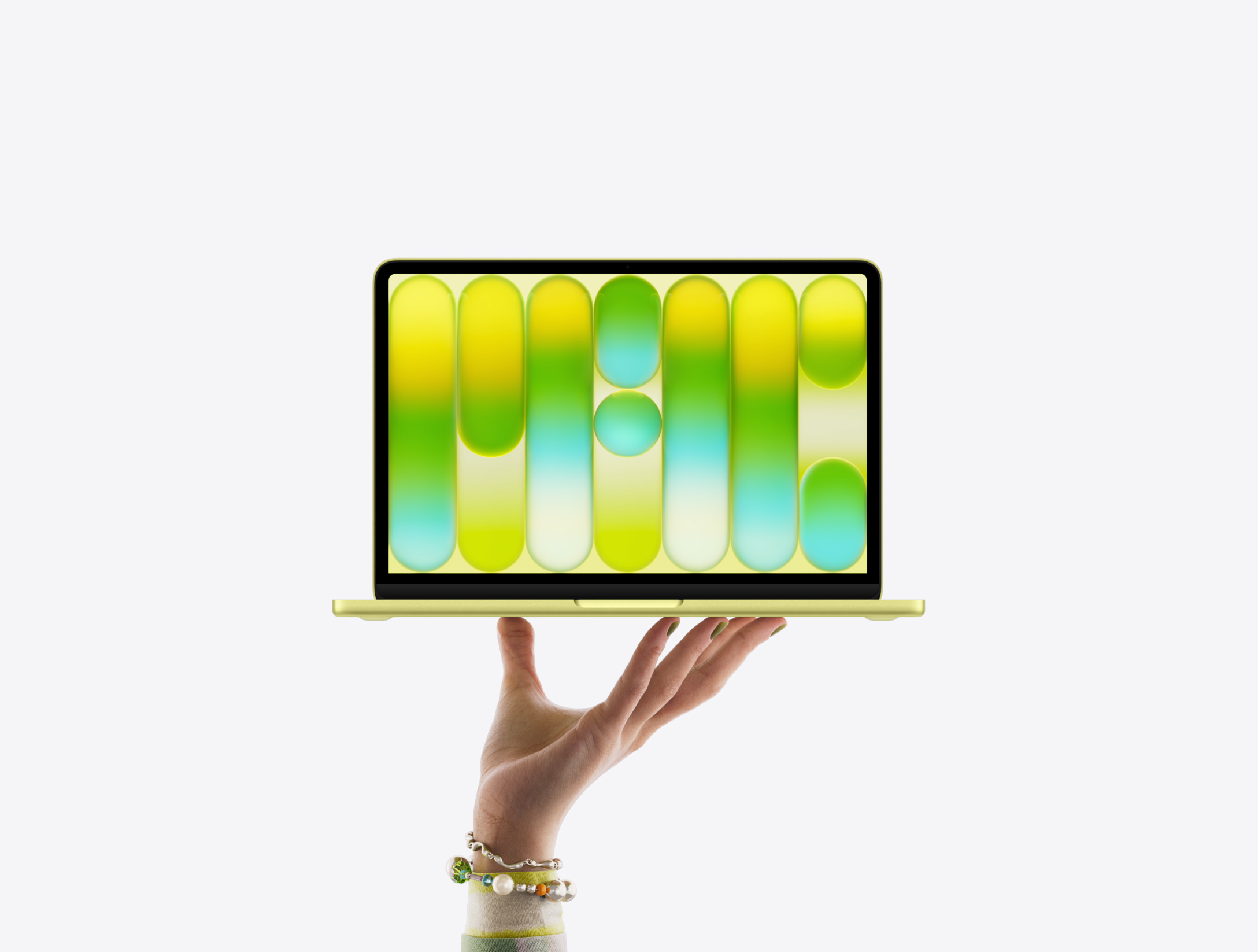 開いた手の指先がシトラスのMacBook Neoをバランス良く支えている。画面にはカラフルで抽象的なパターンが表示されている