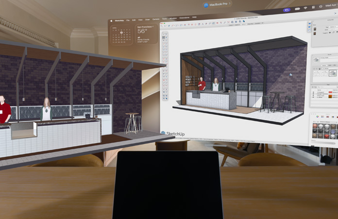 Apple Vision Pro Ansicht, ein MacBook Pro steht auf einer Oberfläche, hinter der 3D Modelle projiziert werden; sie zeigen einen Tresen in einem Café mit zwei dahinterstehenden Personen